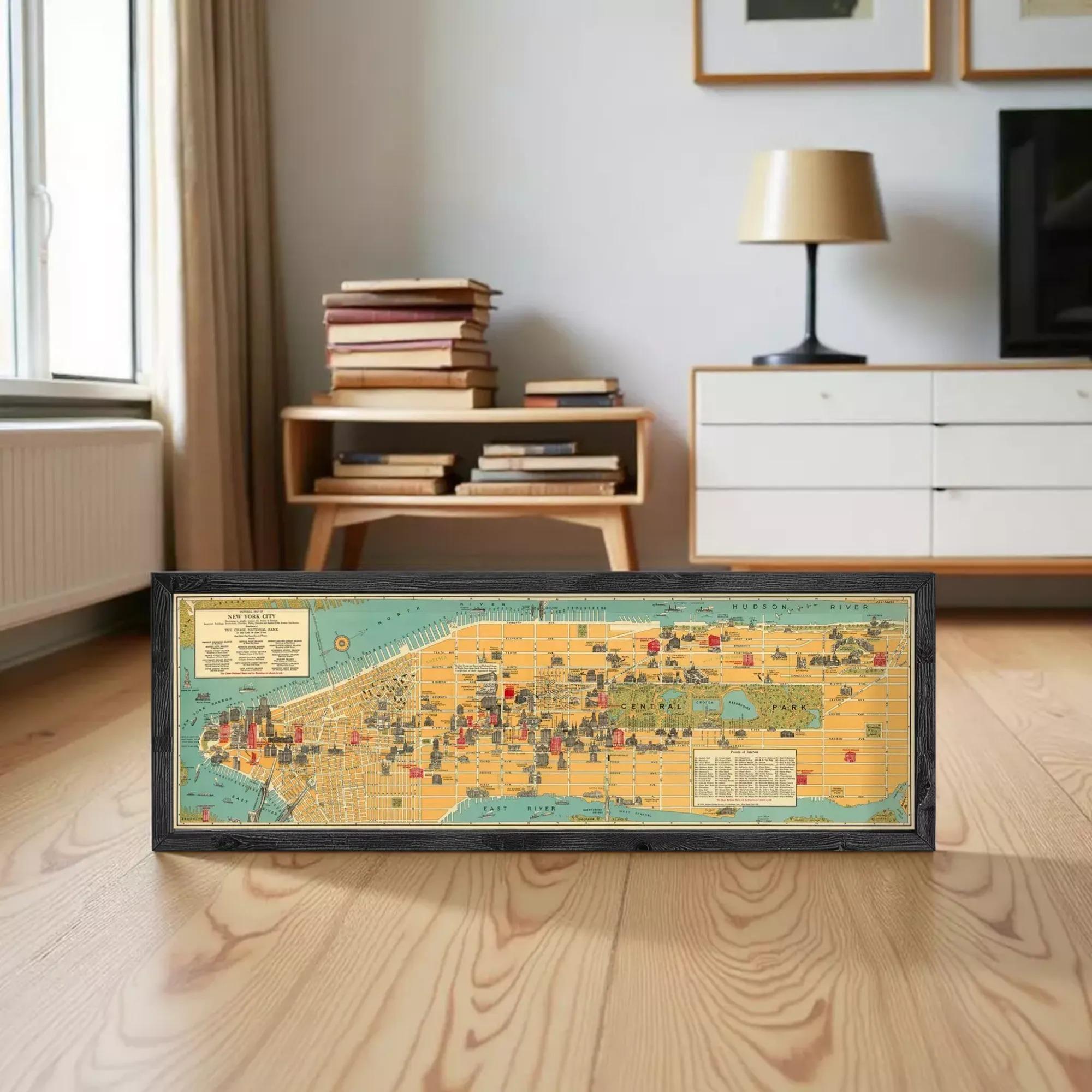 A framed vintage map of New York City is displayed on a wooden floor in a living room setting.