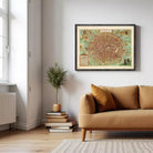 a cozy living room with a brown sofa, a stack of books, a potted plant, and a framed map of a city hanging on the wall.
