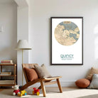 a living room with a wooden chair, a lamp, and a framed map of QuINCY, which is a city in the United States.