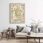 a living room with a large framed map of Scotland hanging on the wall above a couch with pillows. There are also some books and a vase on a table in the room.