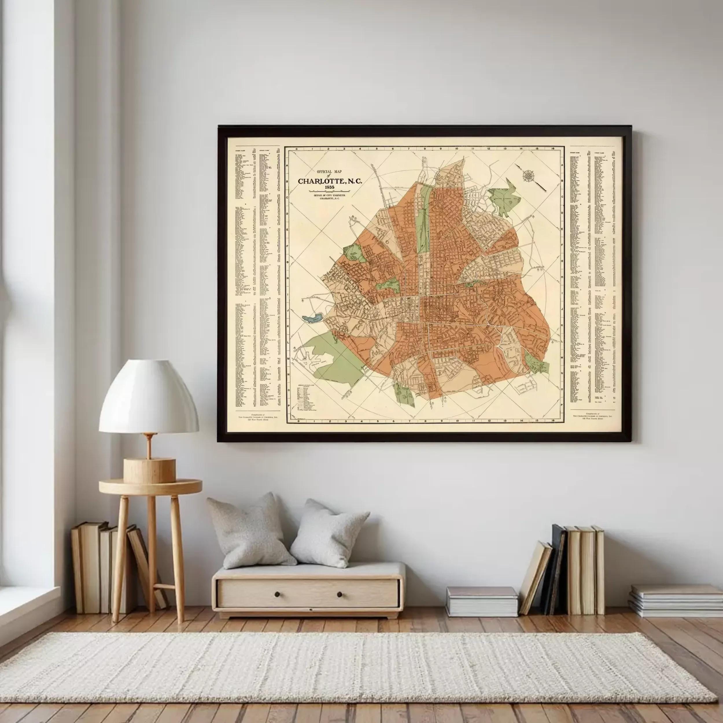 a large framed map of Charlotte, North Carolina, hanging on a wall in a room with a wooden floor and a small table with a lamp.