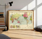 The image is a framed vintage world map with a wooden border, displayed on a white wall.