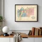 a framed vintage map of the city of Utica, New York, hanging on a wall above a wooden bookshelf filled with books.