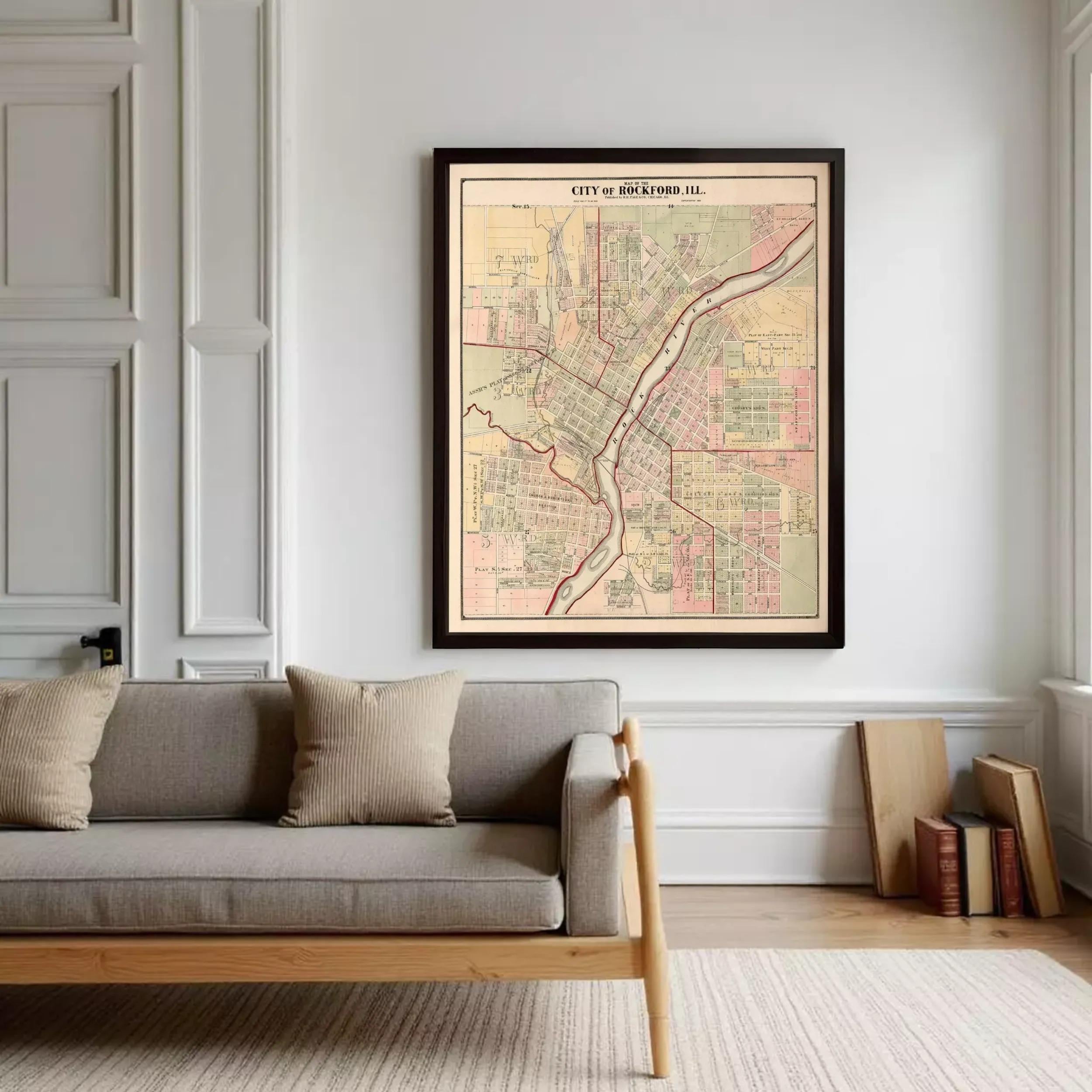 a large framed map of Cincinnati, Ohio, hanging on a white wall above a gray sofa with two pillows.