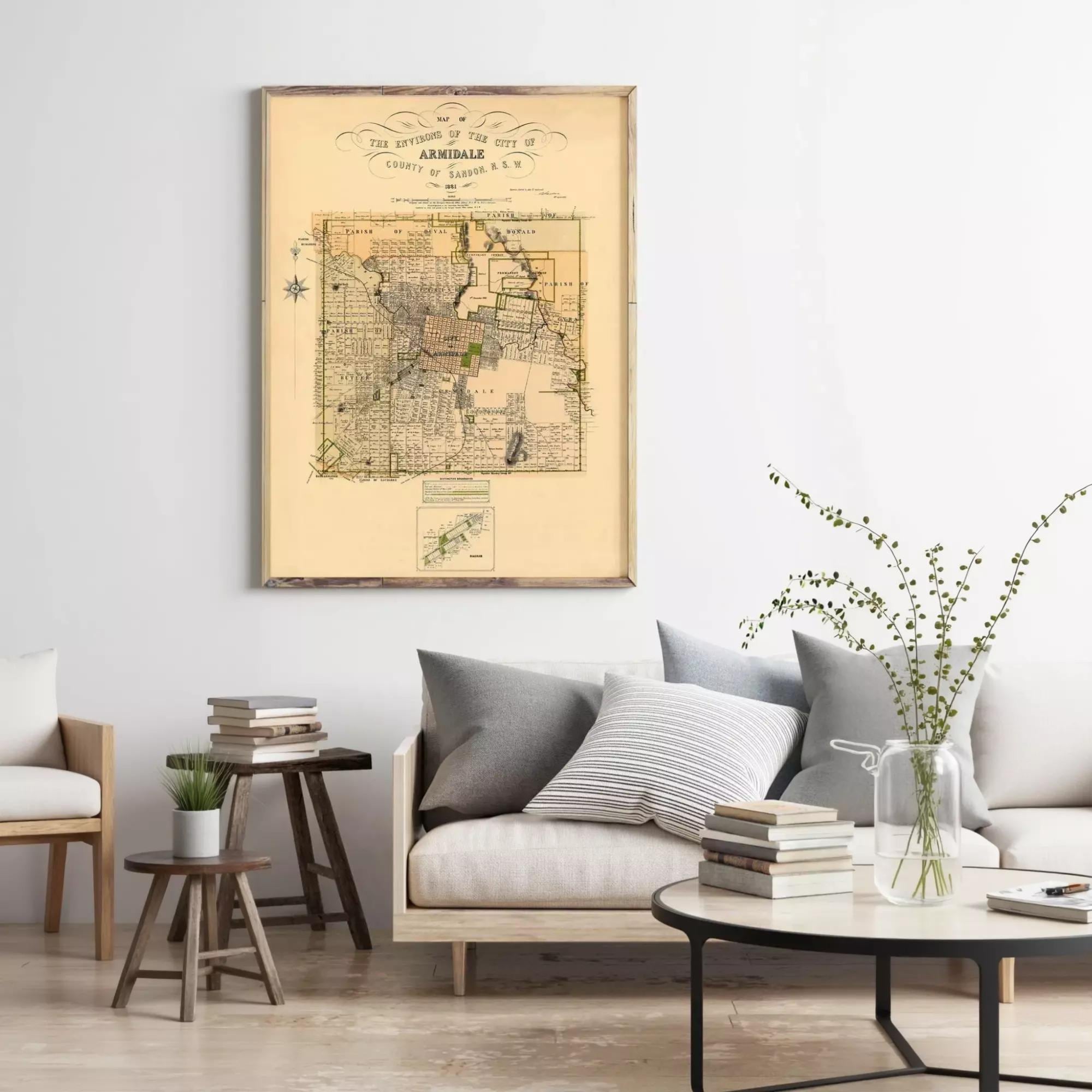 a living room with a large framed map of the city of Armingale hanging on the wall, a comfortable couch with pillows, a coffee table with books and a vase of greenery, and a wooden stool in the corner.