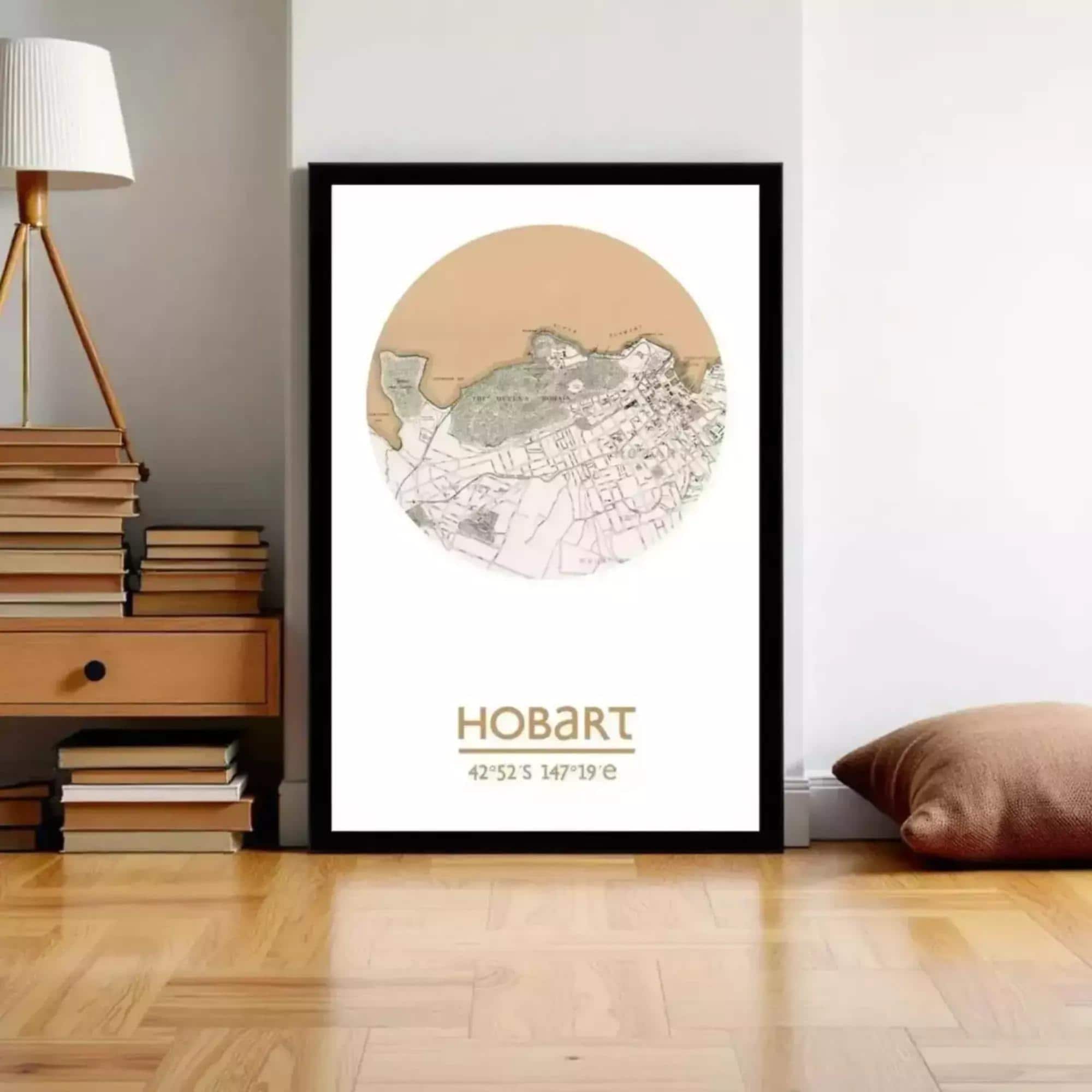 A framed map of Hobart, Australia, with the text "HOBART 42-52-46-19 e" printed on it, is displayed on a wall in a room with a lamp and bookshelf.