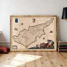 The image is a framed antique map of the island of Cyprus, featuring detailed cartography and maritime imagery.