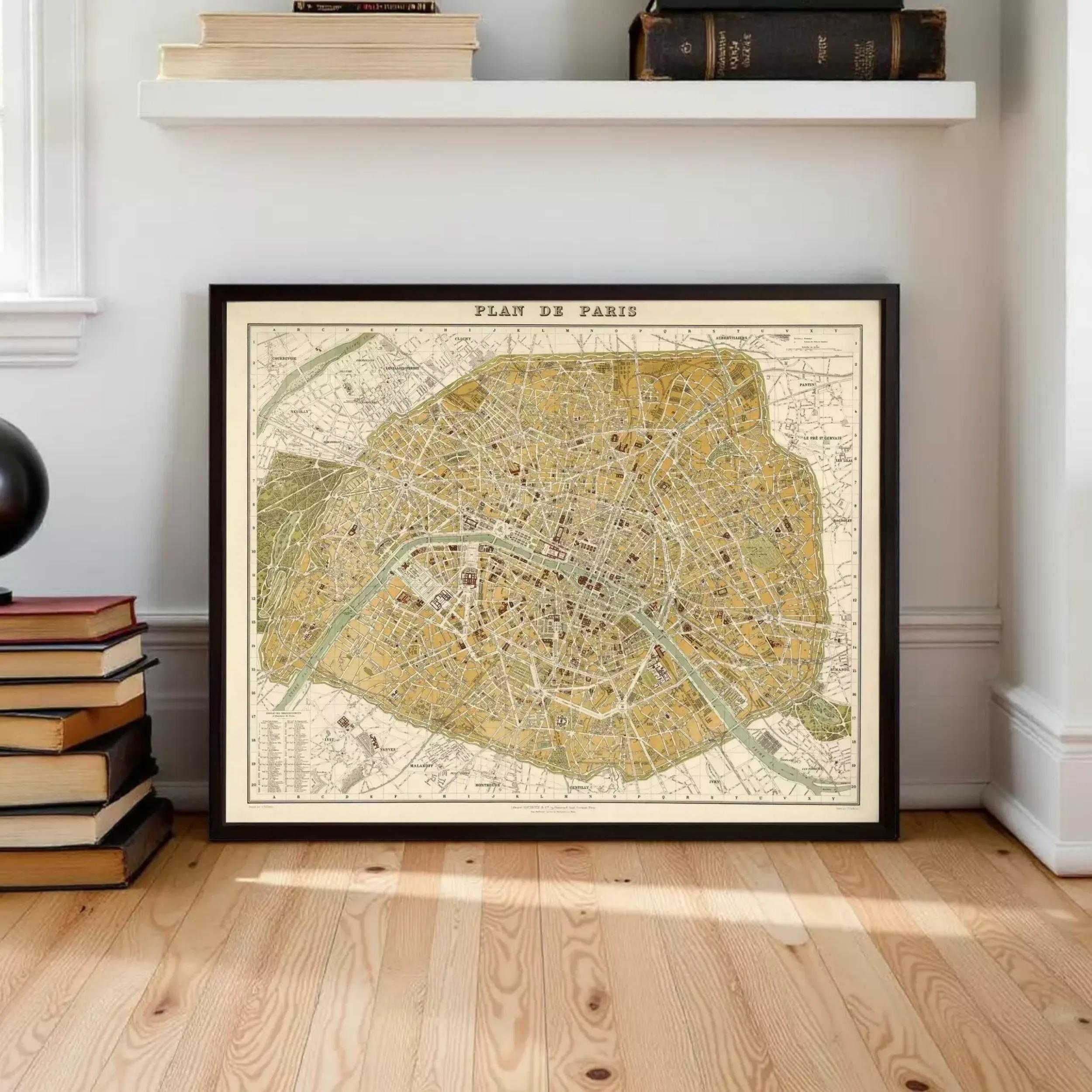 A framed map of Paris, France, displayed on a wooden floor in a room with a shelf and books.