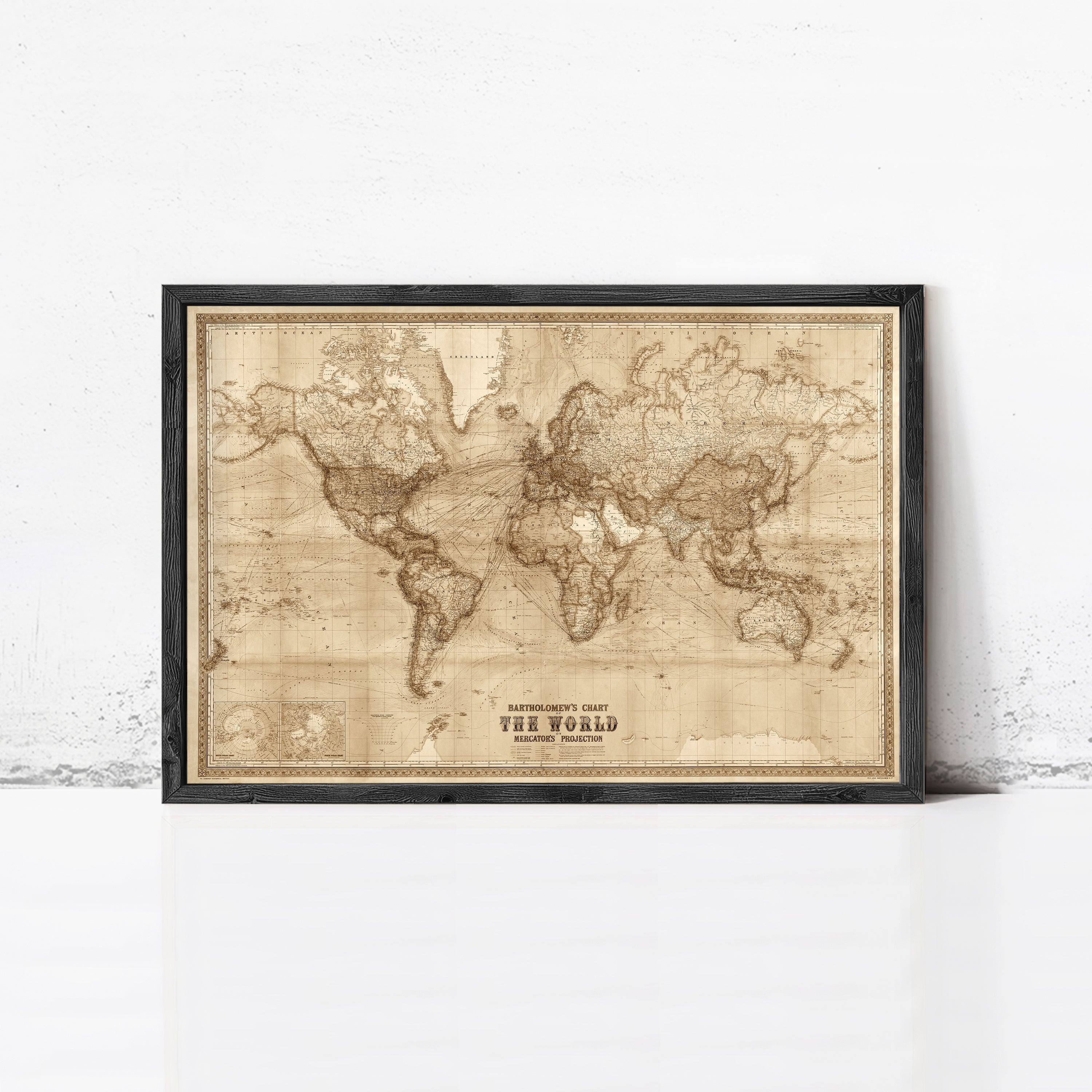 The image is a framed vintage world map with a black border, displayed on a white wall.