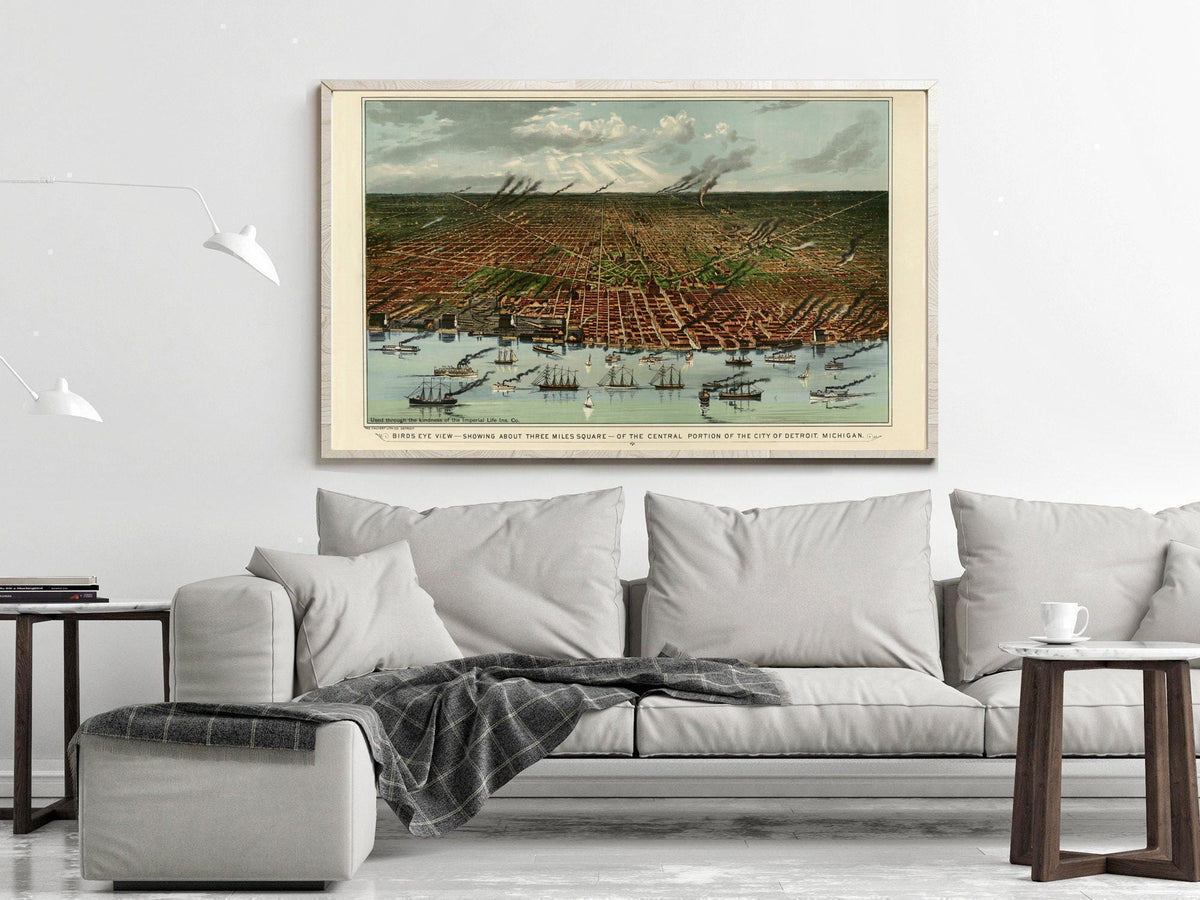 a large framed painting of a cityscape with boats in the foreground, hanging on a wall above a gray couch in a living room setting.