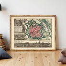 The image is a framed vintage map of a city, depicting a detailed layout of the city's streets, buildings, and surrounding landscape.