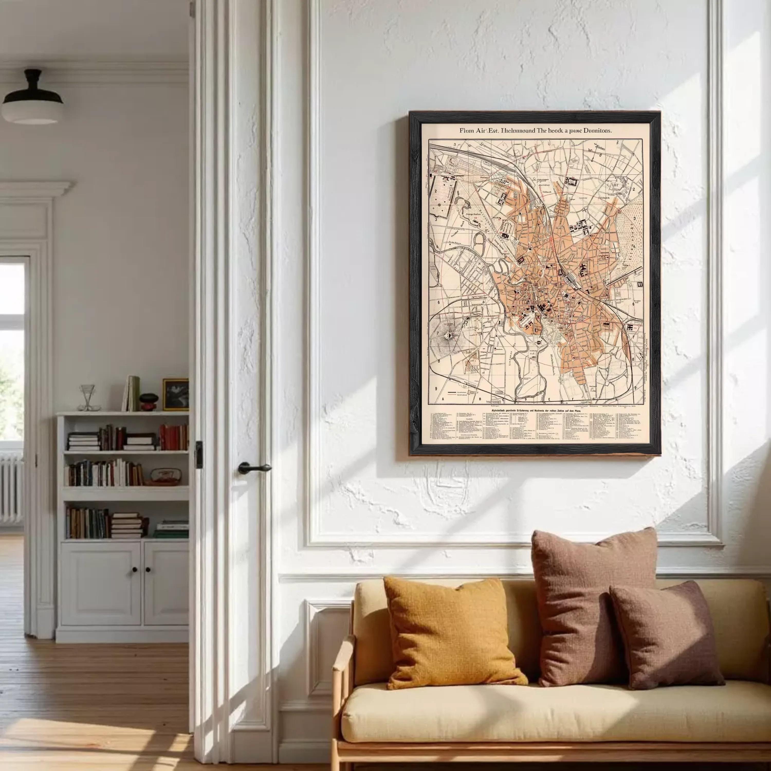 a cozy living room with a large framed map of a city hanging on the wall above a beige sofa with brown pillows.
