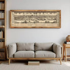 a large, framed map of a city hanging on a wall above a gray sofa in a living room.