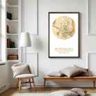 a cozy living room with a large framed map of Plymouth, Massachusetts, hanging on the wall. The room has a comfortable seating area with a bench and a chair, and there are bookshelves filled with books.
