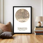 A framed poster of a map of Toronto, with the text "TORONTO" and the location "43°42'49" N 79°24'49" W" printed on it.