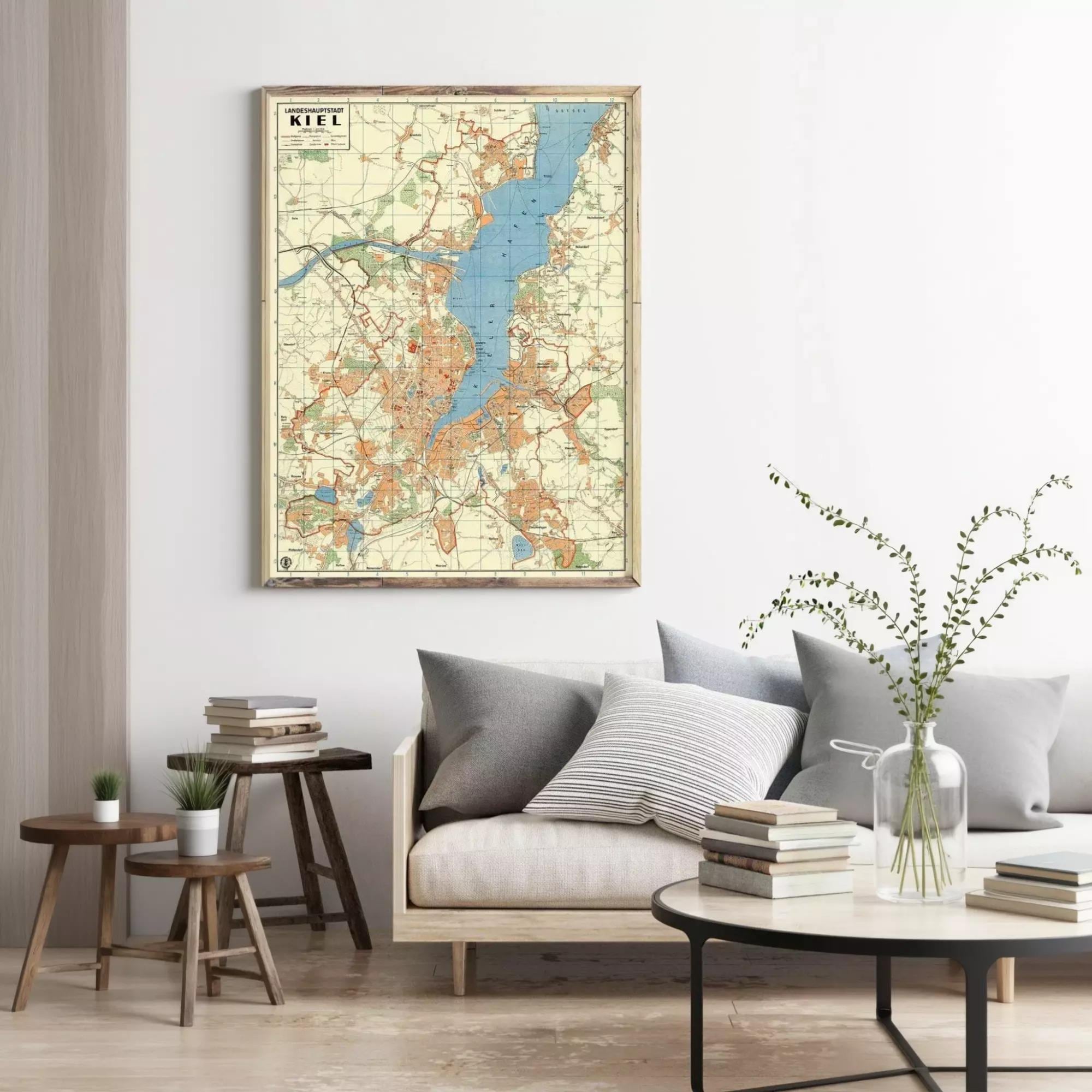 a living room with a large framed map of Lake Titicaca hanging on the wall above a couch with pillows. The room also includes a coffee table with books and a vase of greenery.