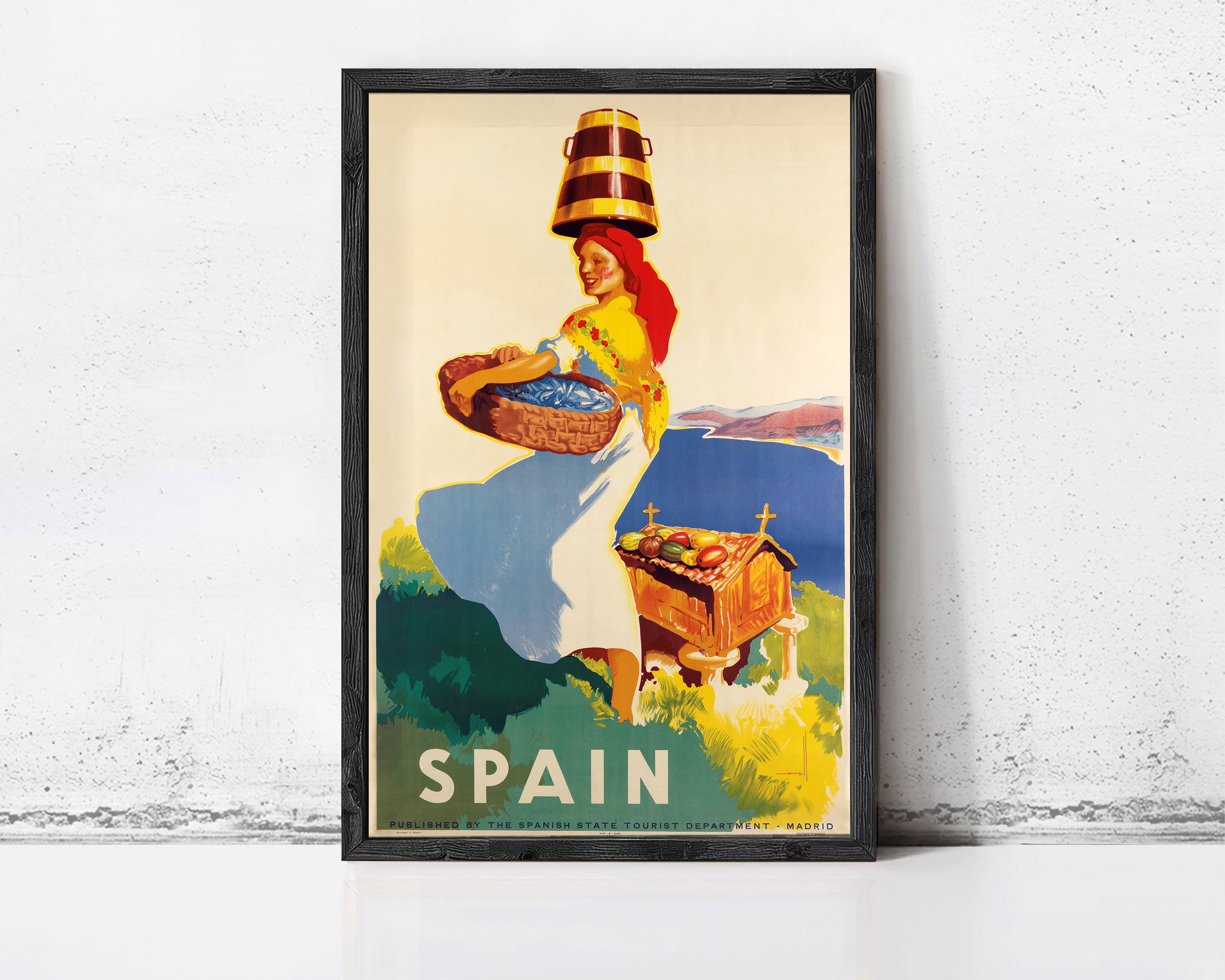 A framed vintage travel poster depicting a woman carrying a basket of fruit, with the word "SPAIN" prominently displayed.