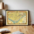 a framed map of the city of Seville, Spain, displayed on a wooden floor in a room with a lamp and books.