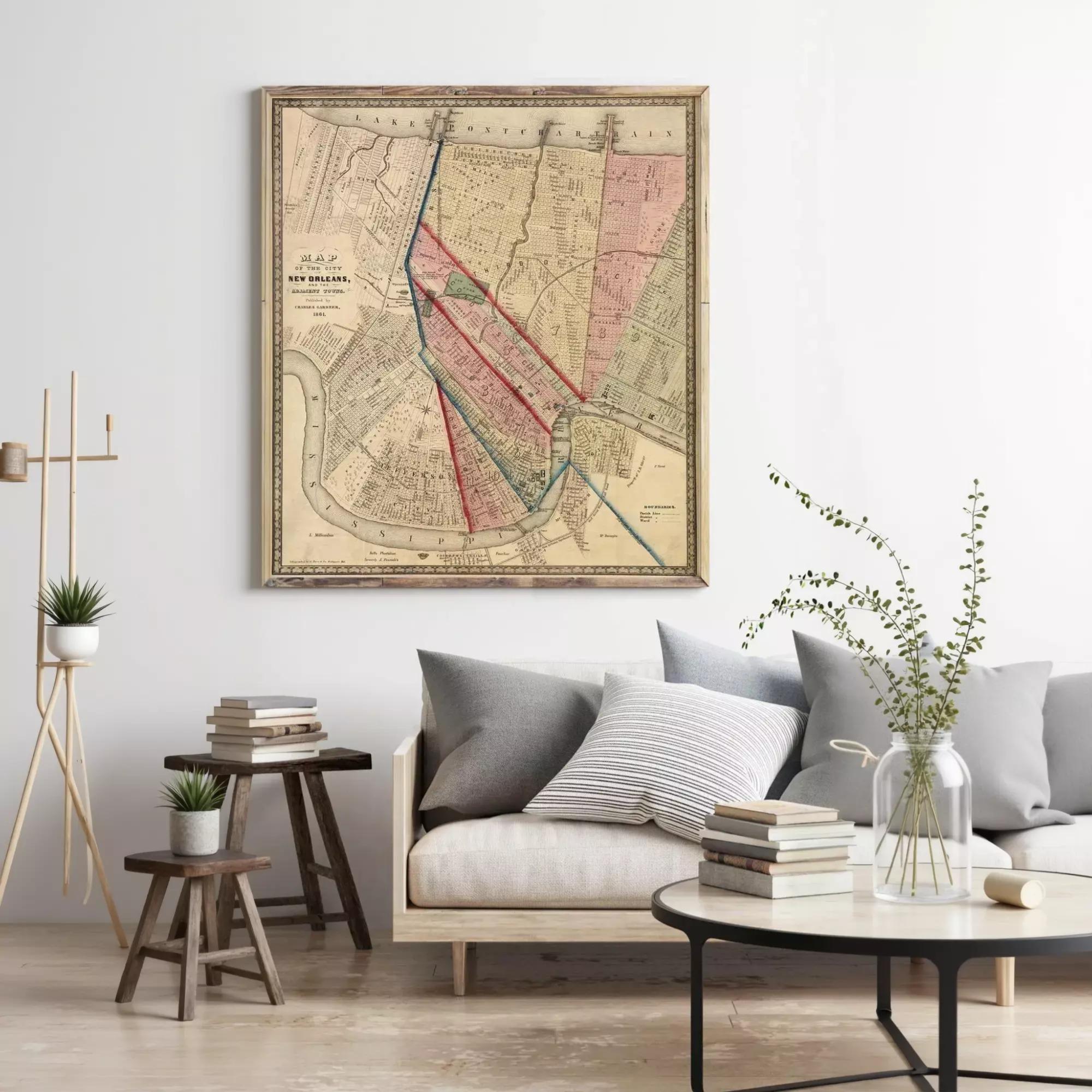 a living room with a large framed map hanging on the wall above a couch with pillows. There are also some books and a vase with greenery on the coffee table.