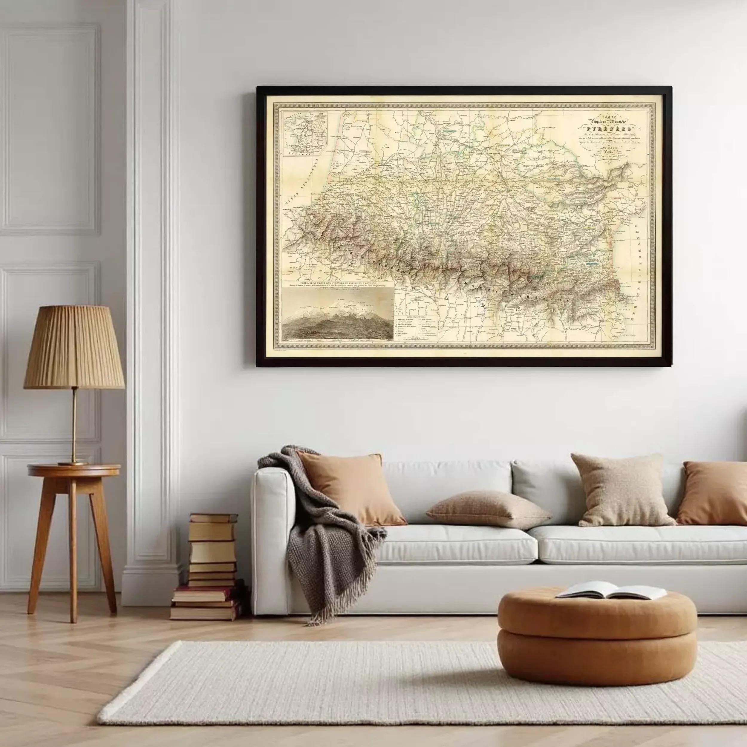 a large framed map hanging on a white wall above a white couch with brown pillows. There are also some books and a lamp on a side table in the room.