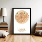 A framed map of Nimes, France, with a wooden floor and a stack of books on either side.