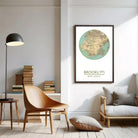 a living room with a wooden chair, a bookshelf filled with books, and a framed map of Brooklyn hanging on the wall.