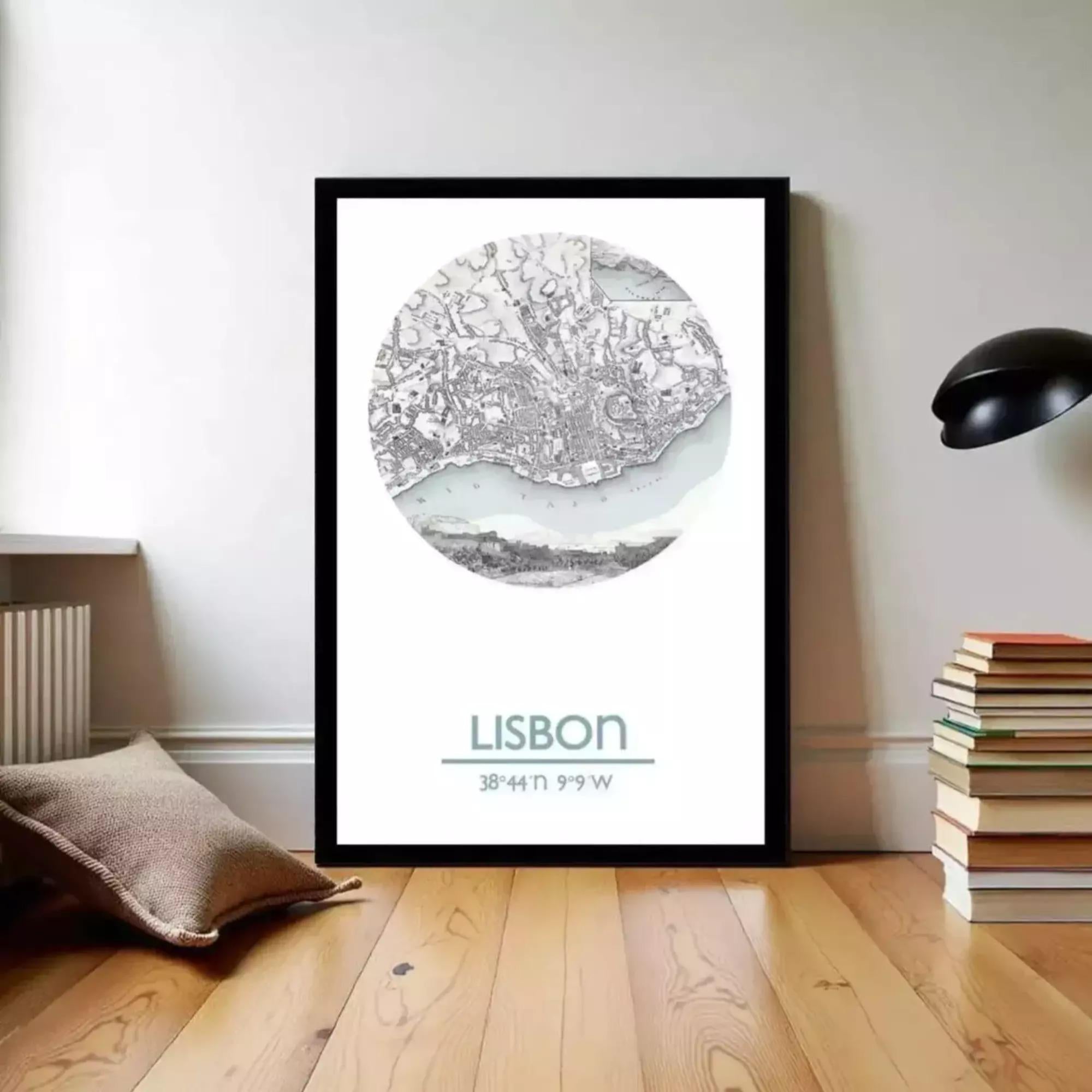 A framed poster of a map of Lisbon, Portugal, displayed on a wall in a room with a stack of books and a lamp.