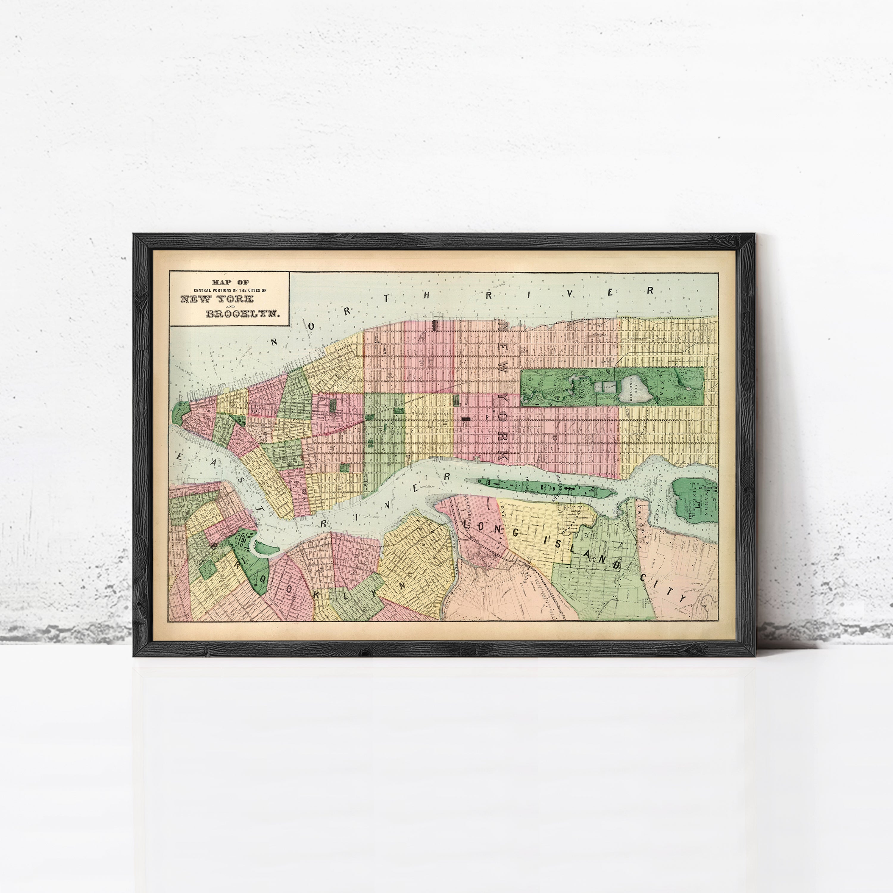 The image is a framed map of New York City, depicting the city's streets and neighborhoods in a vintage style.