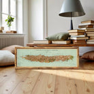A framed map of the island of La Nouvelle, Caledonie, displayed against a white wall.