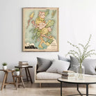 a living room with a large framed map of Scotland hanging on the wall above a couch with pillows. There are also some books and a vase with flowers on the couch, creating a cozy and inviting atmosphere.