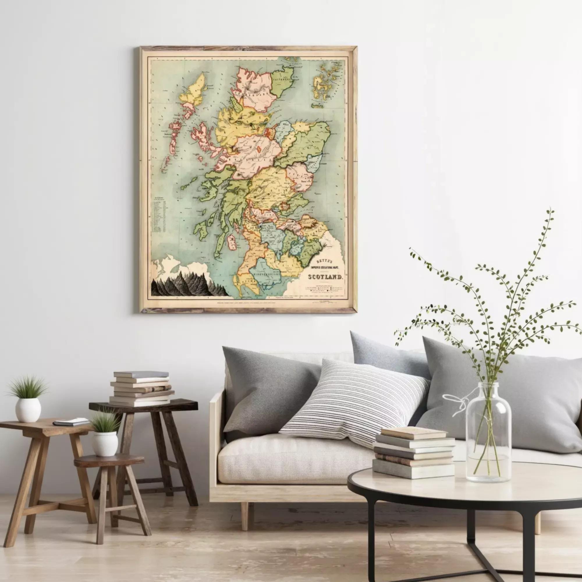 a living room with a large framed map of Scotland hanging on the wall above a couch with pillows. There are also some books and a vase with flowers on the couch, creating a cozy and inviting atmosphere.