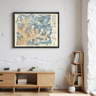 a framed map of the Rocky Mountains hanging on a wall, with a wooden cabinet below it and a bookshelf to the right.