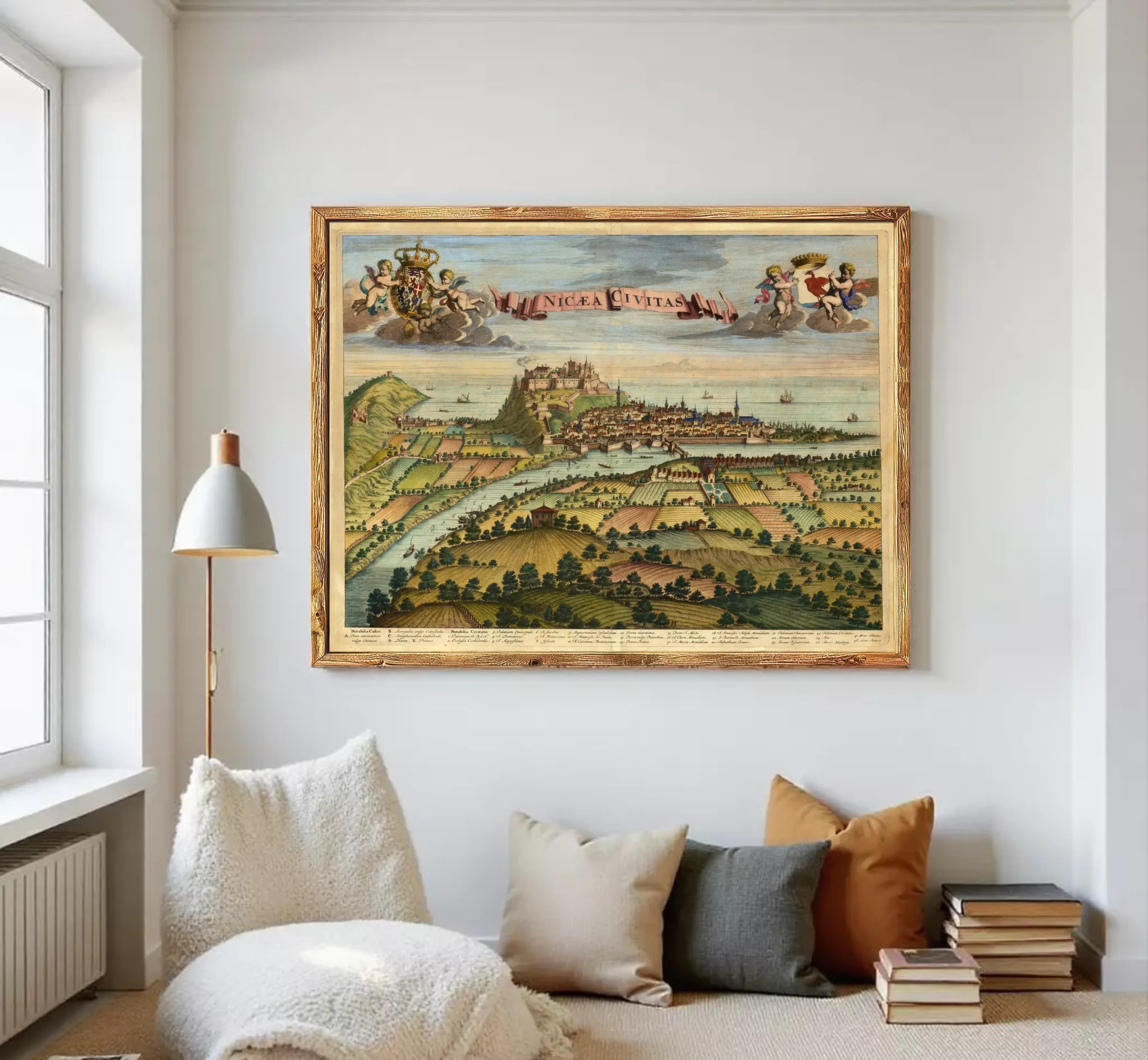 The image is a framed painting depicting a cityscape with a river, mountains, and clouds in the background.