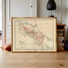 a framed map of Costa Rica, with a wooden floor and a lamp in the background.