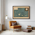a cozy living room with a large framed map of the Caribbean hanging on the wall, a comfortable brown armchair, a stack of books, and a lamp on a side table.