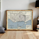 A framed map of Toronto, Canada, depicting the city's streets and surrounding areas, is displayed on a wooden floor.