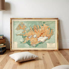 a large framed map of Iceland, with a wooden floor and a stack of books in the background.
