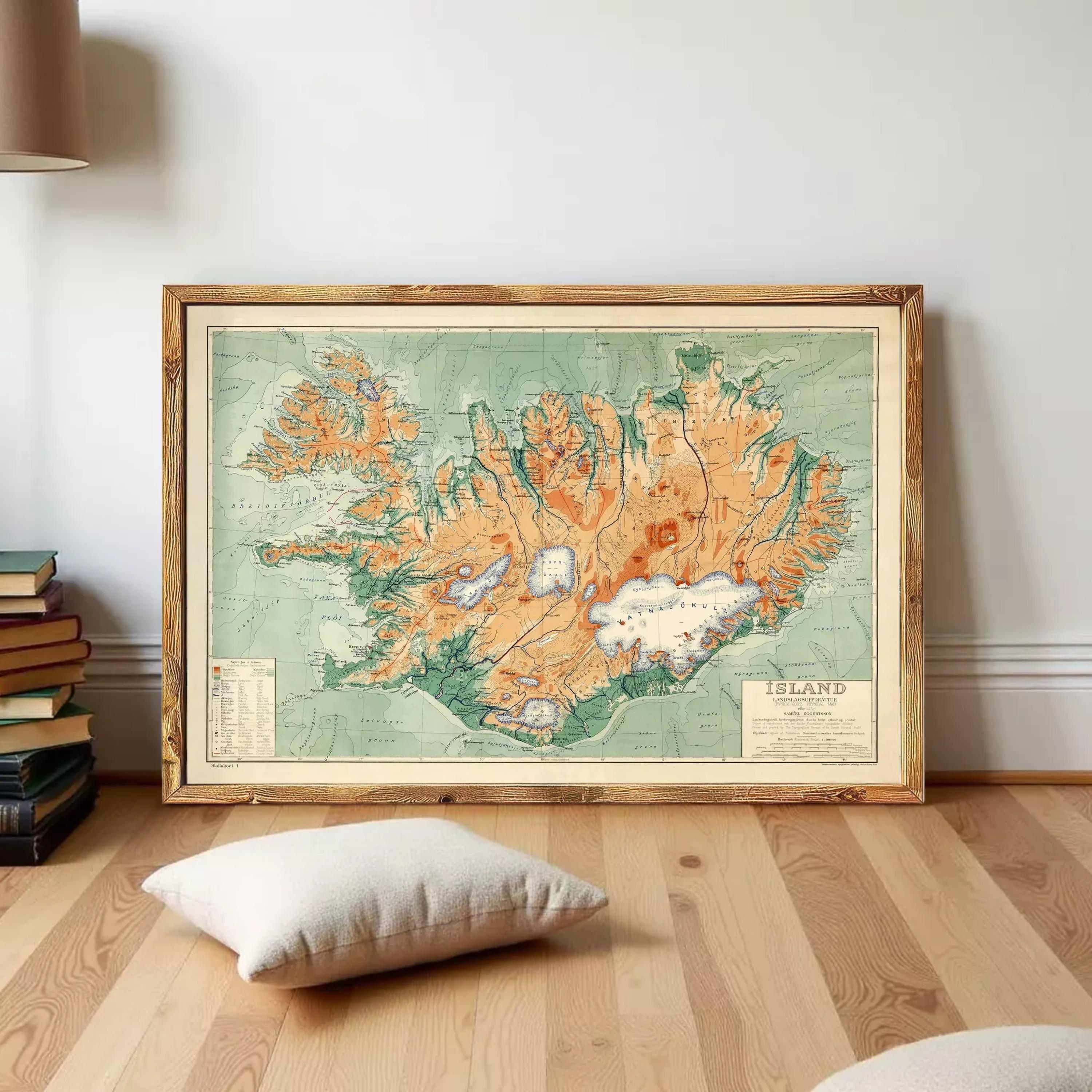 a large framed map of Iceland, with a wooden floor and a stack of books in the background.