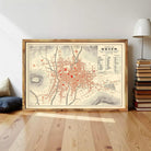 a framed map of Quito, the capital city of Ecuador, with a wooden floor and a stack of books in the background.