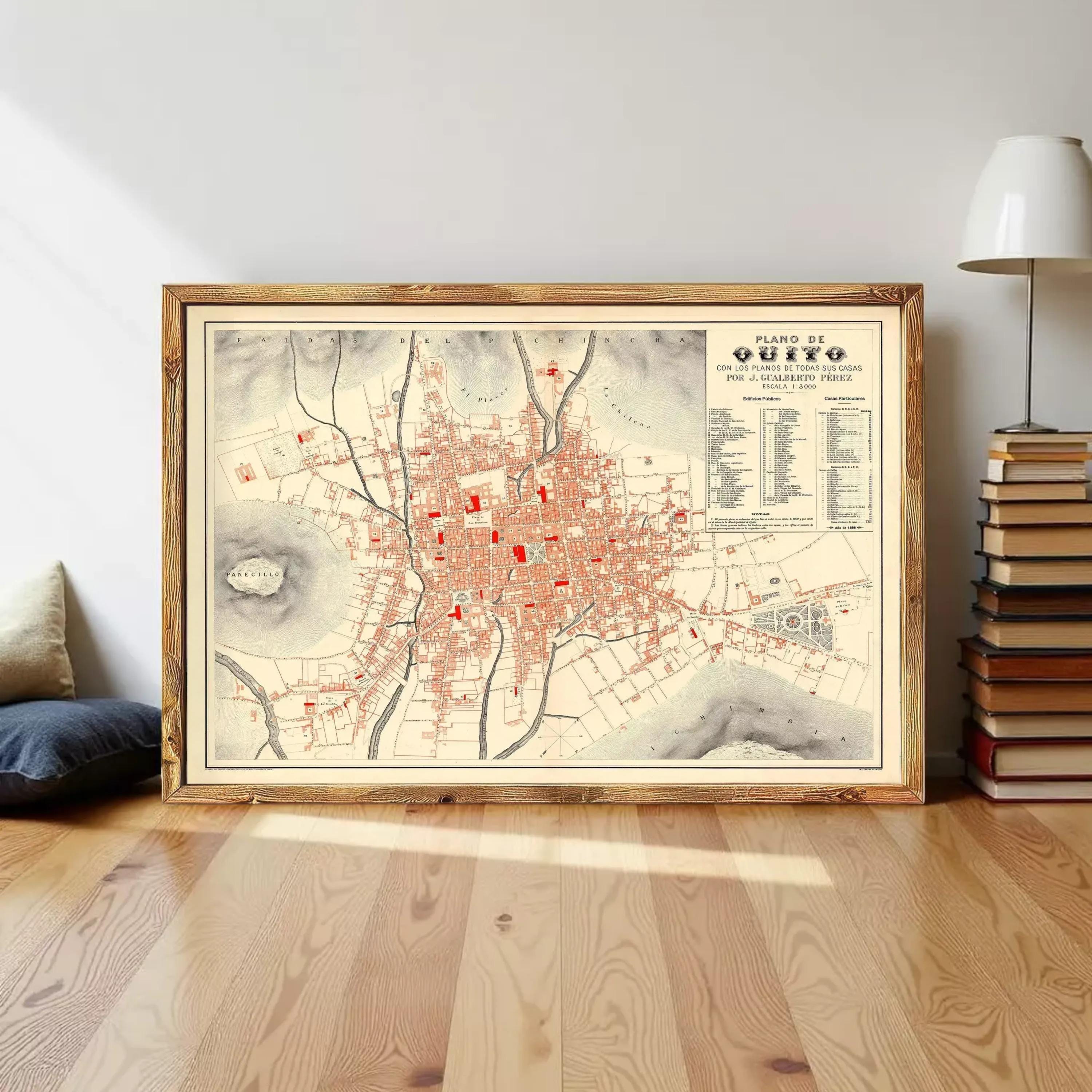 a framed map of Quito, the capital city of Ecuador, with a wooden floor and a stack of books in the background.