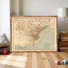 a framed map of Singapore, with a wooden floor and a stack of books in the background.