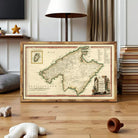 a framed map of the Mediterranean region, with a lamp and books in the background.