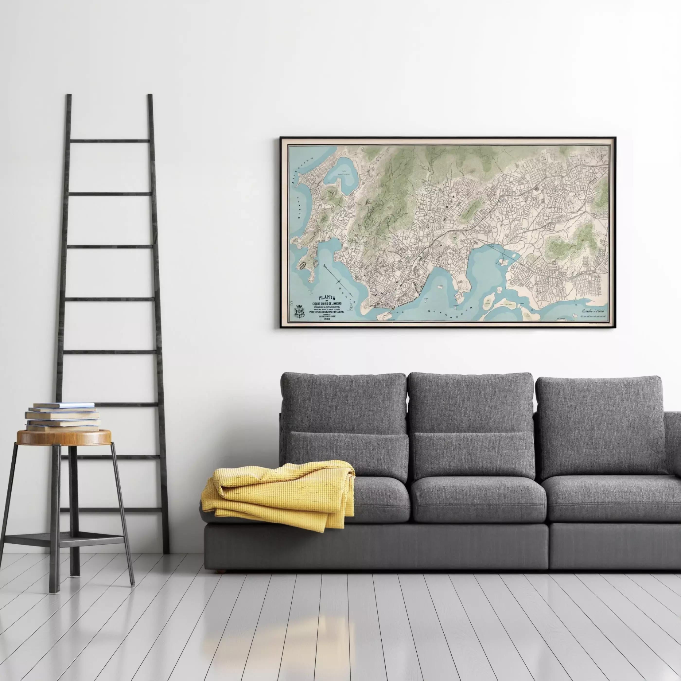 a gray couch with a yellow blanket draped over it, and a large framed map of a city hanging on the wall above the couch.
