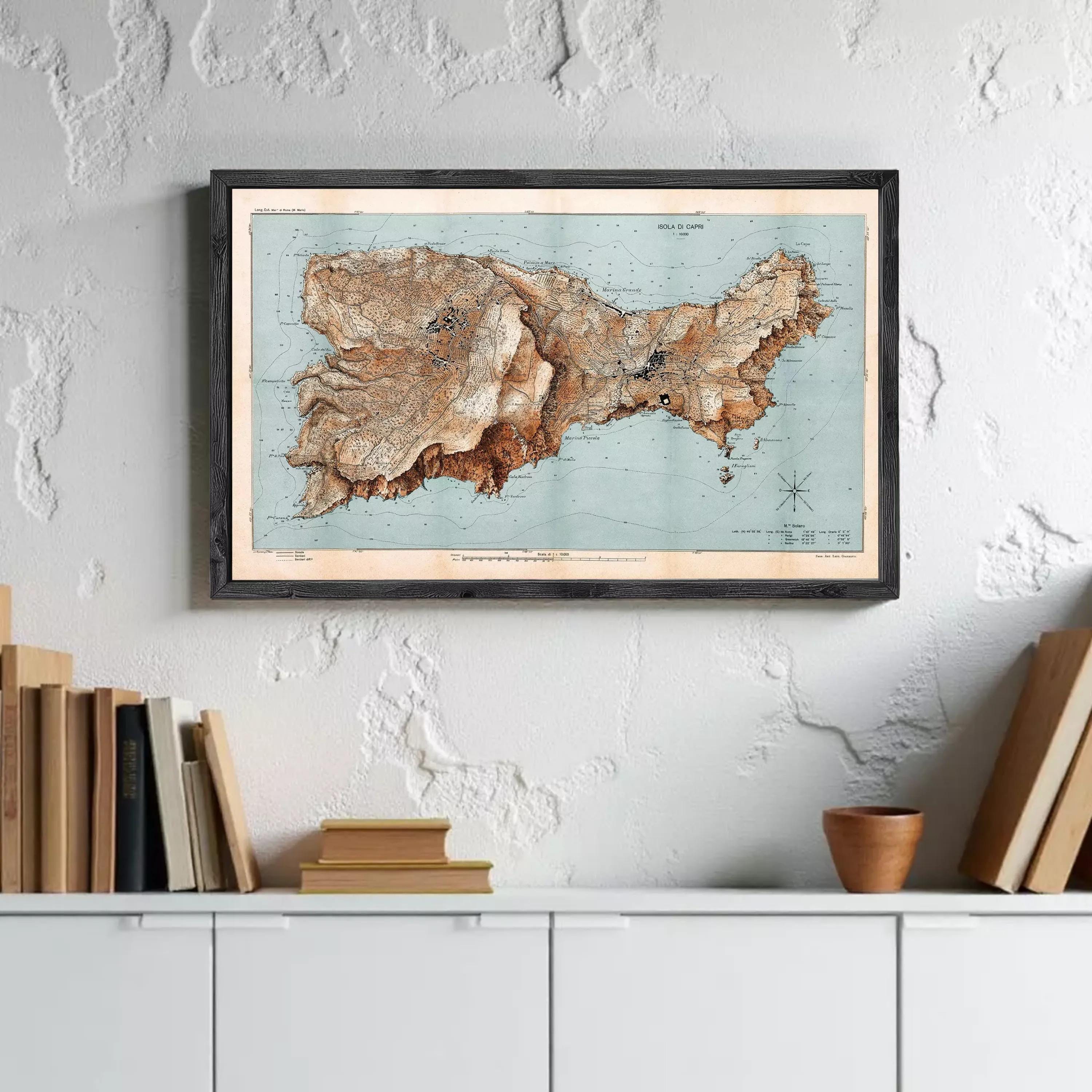a framed map of a region hanging on a wall above a white cabinet with books and a small wooden object on top.