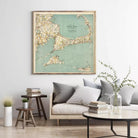 a living room with a large framed map of Cape Cod hanging on the wall above a couch with pillows. There are also some books and decorative items on the couch and table below the map.