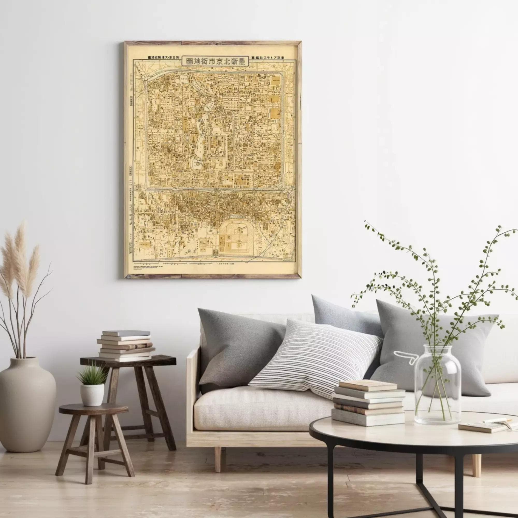 a living room with a large wall-mounted map of a city, a gray sofa with striped pillows, a wooden side table, and a round coffee table with books and a vase of greenery.