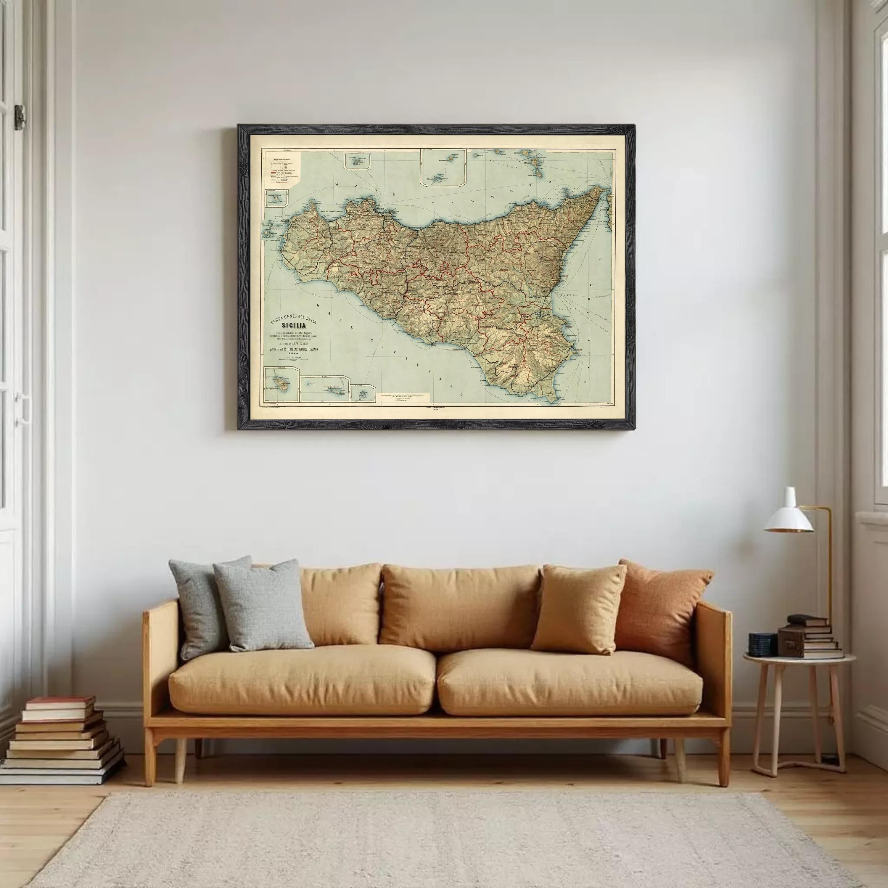 a large framed map of Sicily hanging on a wall above a brown sofa with pillows.