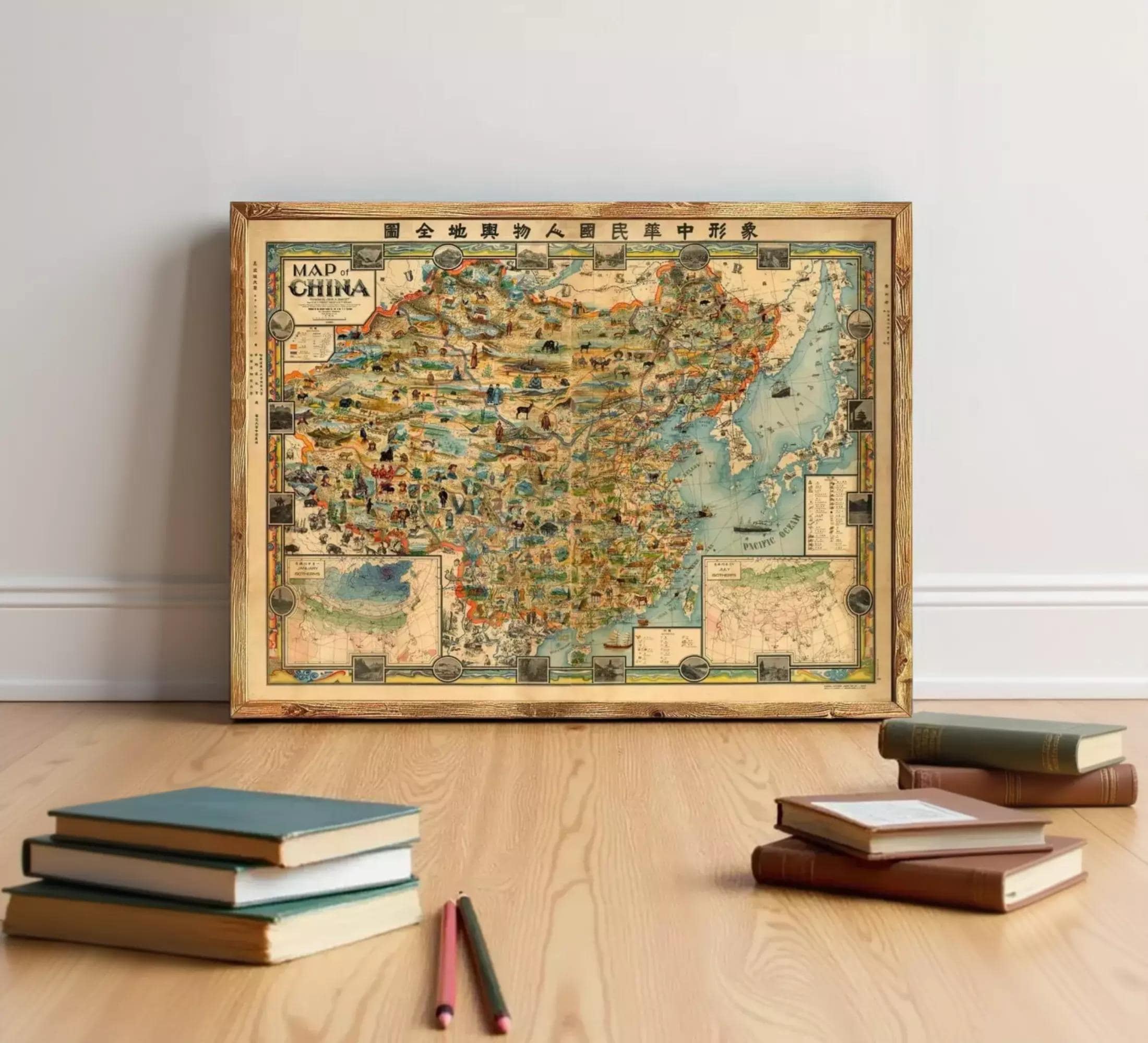 a large, colorful map of China displayed on a wooden floor, with a stack of books and some pencils in the foreground.