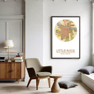 a living room with a large framed map of Little Rock, a town, hanging on the wall. The room has a wooden chair, a lamp, and a bookshelf.