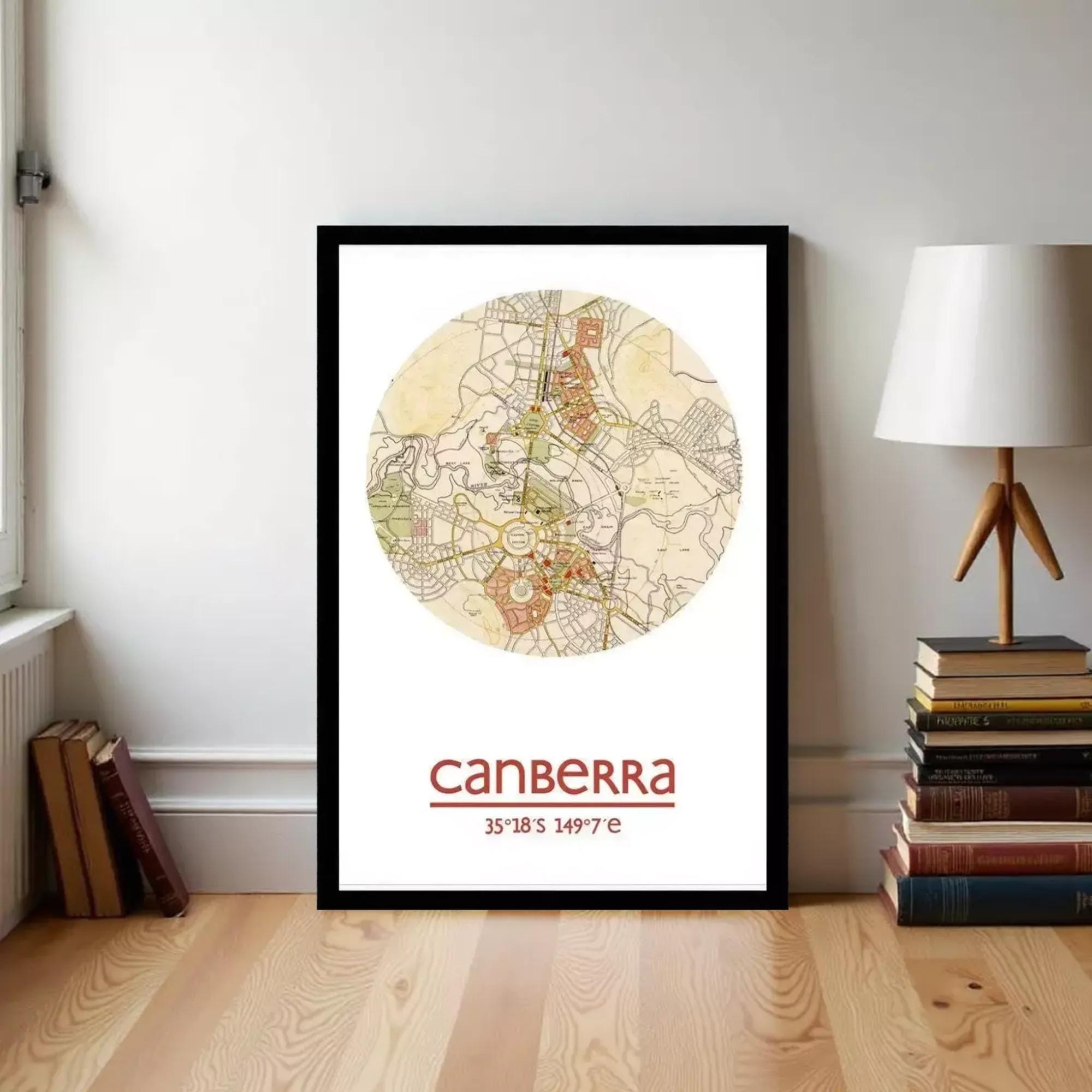 A framed map of Australia with the city of Melbourne highlighted, placed on a wooden floor next to a stack of books and a lamp.